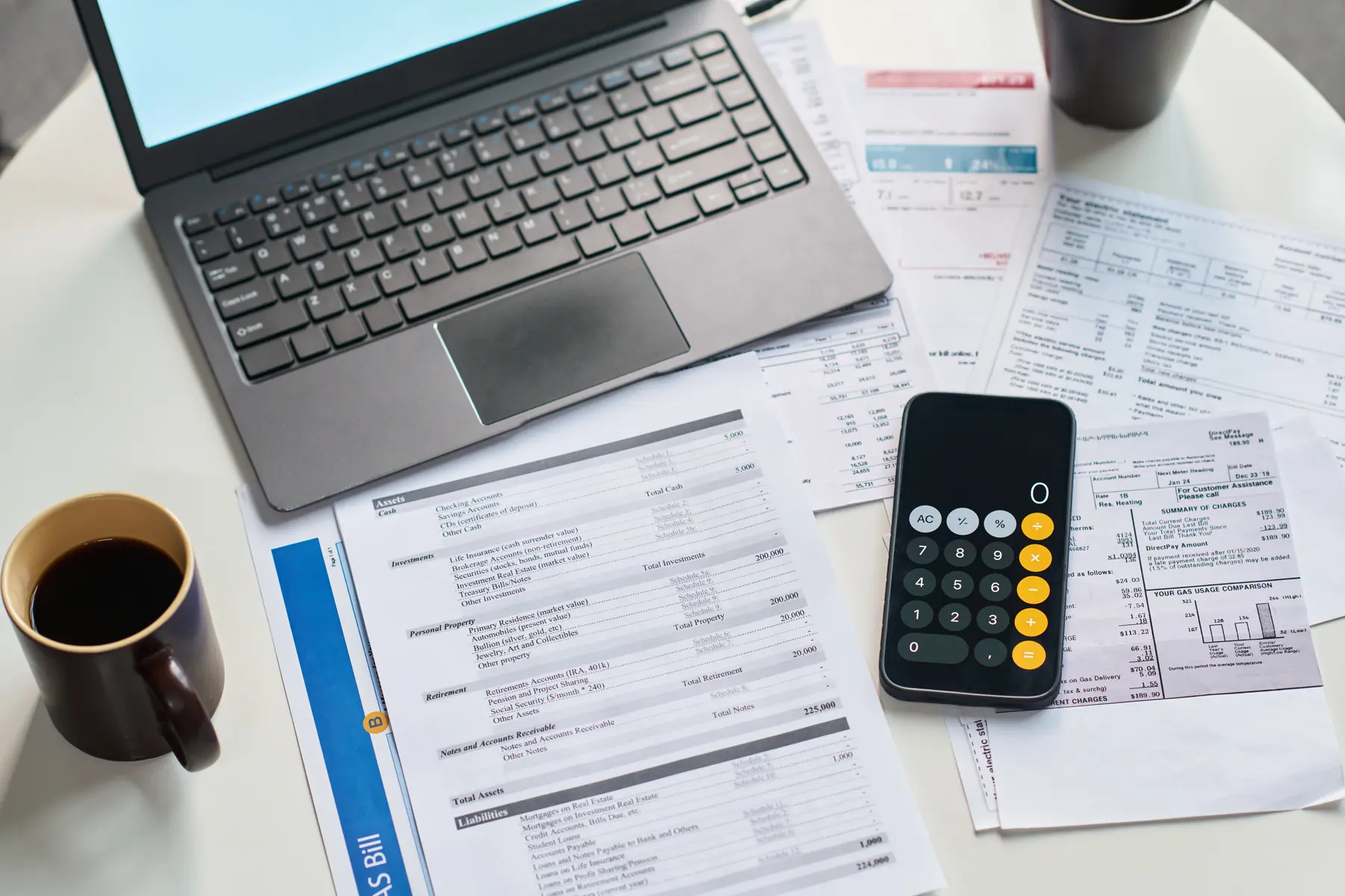 Tax forms, calculator, laptop, and coffee on a desk