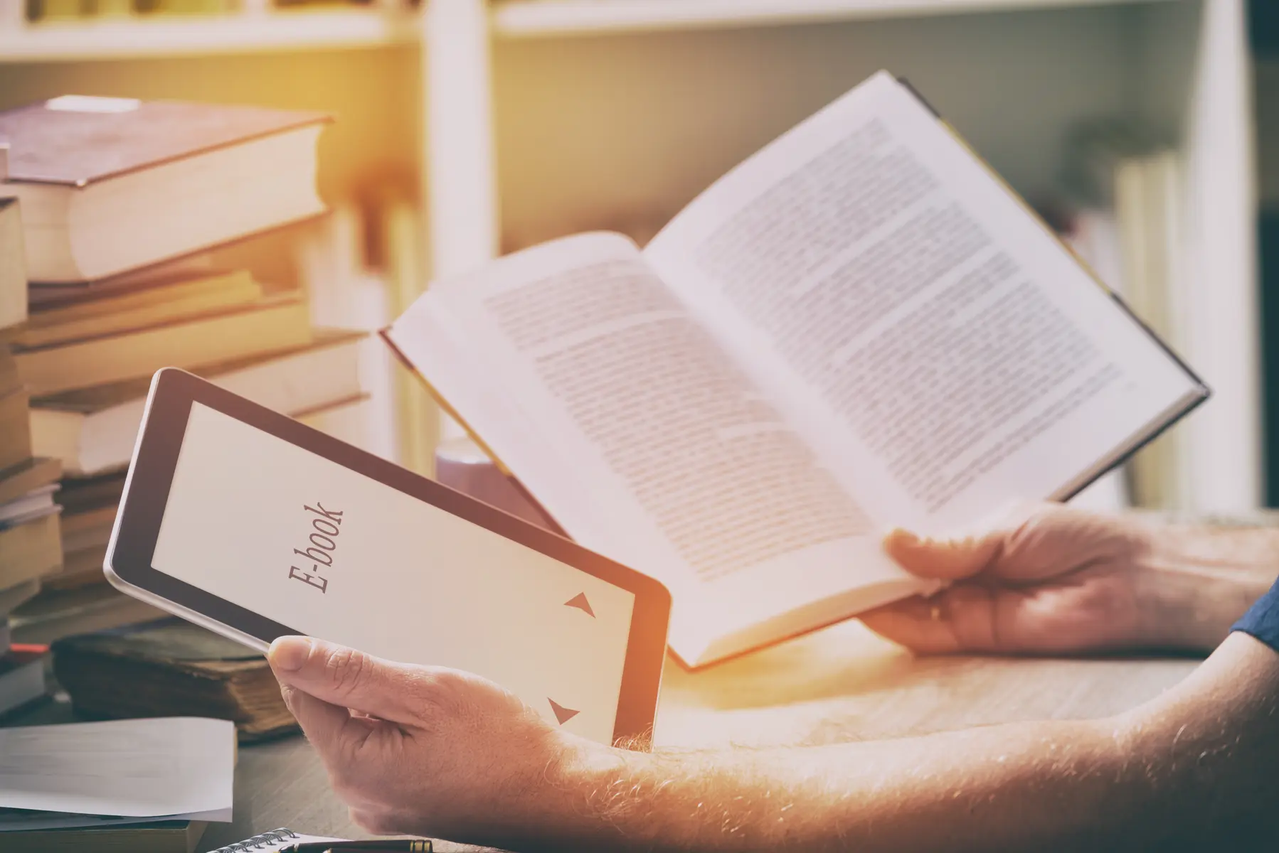 Person reading an ebook beside printed books